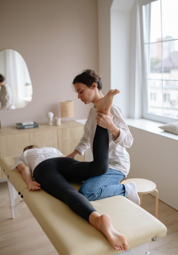 Physiotherapist treating by Holding Patients Leg