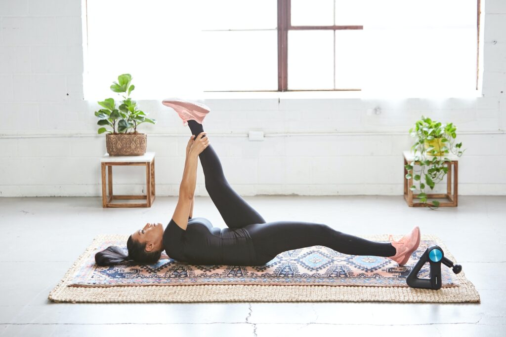 Surprising Benefits of Pelvic Floor Physiotherapy - woman in a black tank top and black leggings lying on a black and white floral area rug